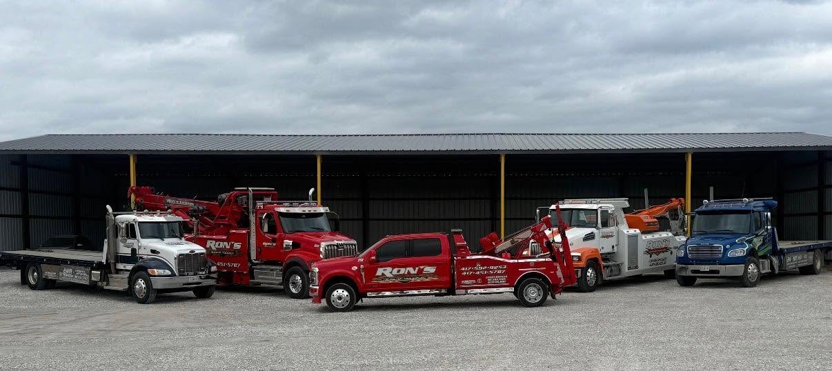 Five Ron's wreckers and flatbeds lined up in front of the shop building in Neosho