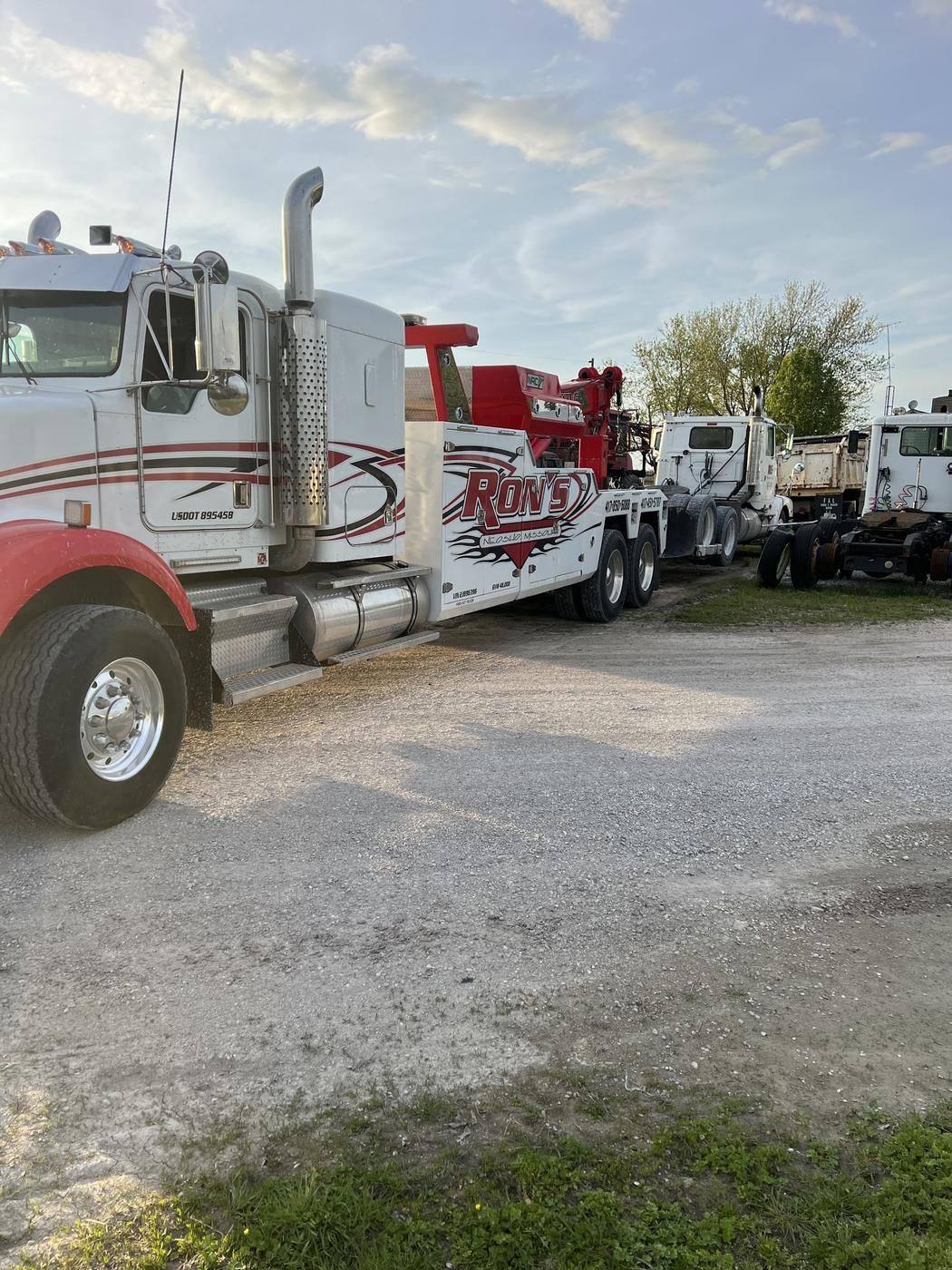 White and red Ron's heavy wrecker parked in the yard