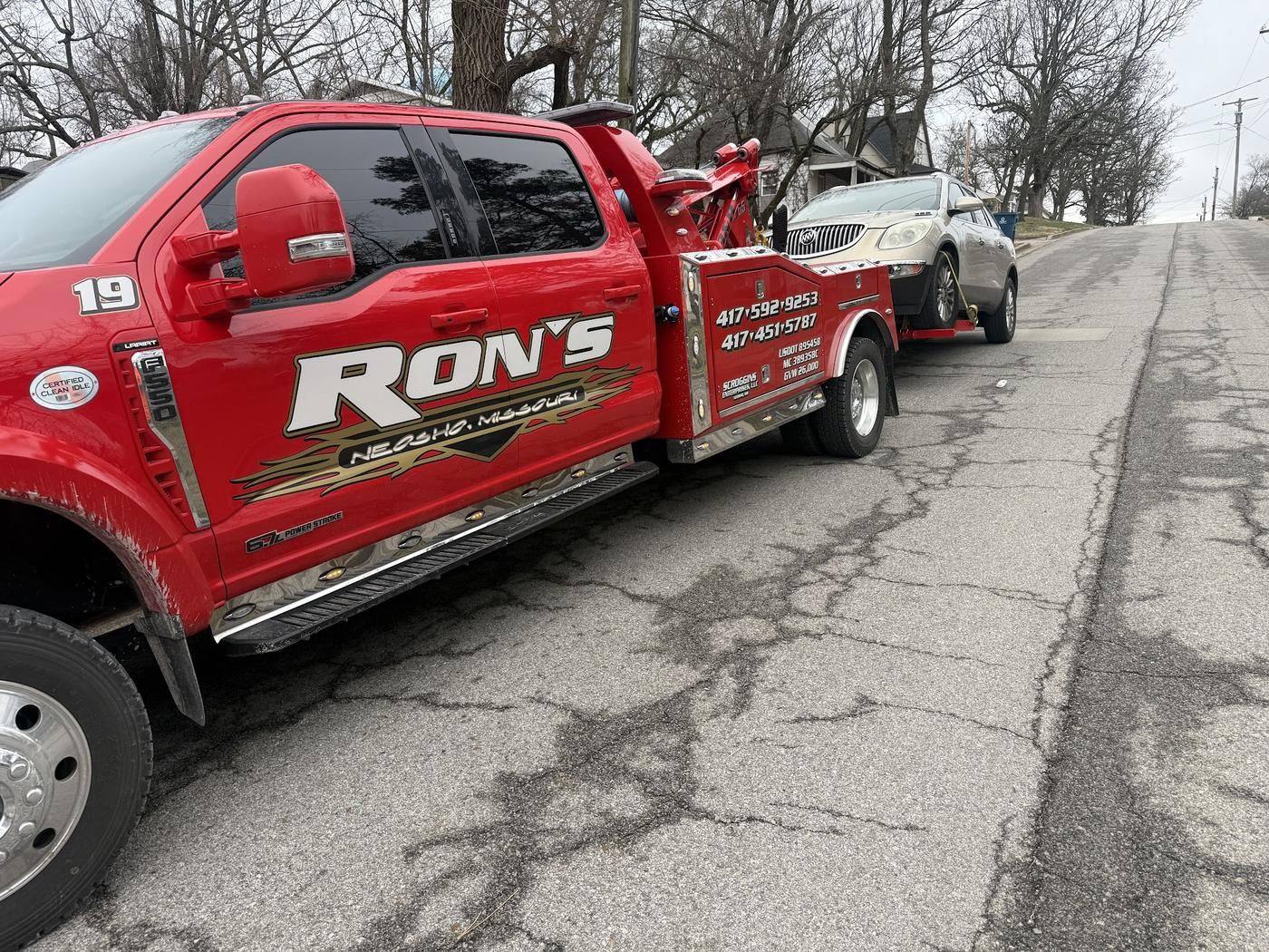Red Ron's wrecker towing an SUV on a residential street